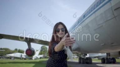 肖像快乐嬉戏的黑发女孩戴着太阳镜在<strong>大飞机</strong>前，看着相机。 夏天。 快乐